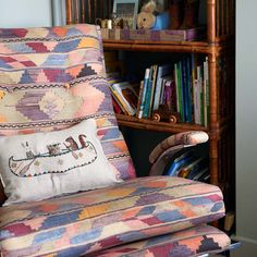 a chair with a pillow on it in front of a bookshelf