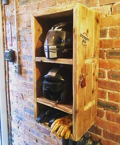 a motorcycle helmet and gloves are on display in a wooden storage unit against a brick wall