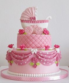 a three tiered cake decorated with pink and white flowers, baby's carriage on top