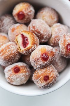 powdered sugar covered doughnuts in a bowl with jam on the top and bottom