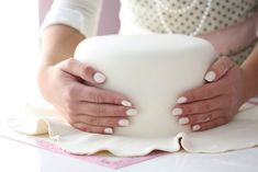 a woman holding a large white bowl on top of a table in front of her