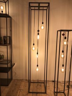 three tall metal and glass lamps with bulbs on them in the corner of a room