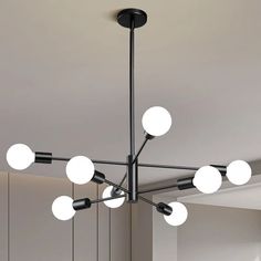 a modern chandelier with eight lights hanging from the ceiling in an empty room