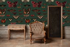 a chair and desk in front of a wall with moths on it, against a green background