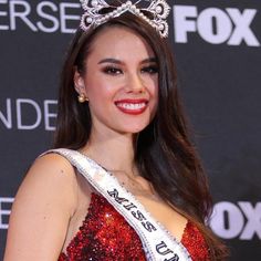 a beautiful woman wearing a tiara and smiling at the camera while standing in front of a black background