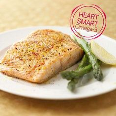 a piece of fish and asparagus on a white plate with a heart smart sticker