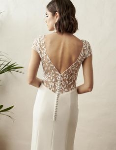 a woman in a white dress with an open back and lace detailing on the top