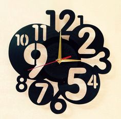 a black clock with numbers on it is hanging from the wall in front of a white background