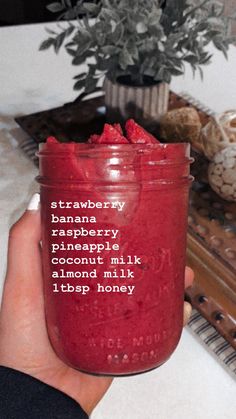 a hand holding a jar filled with raspberry jam