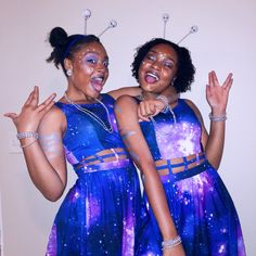 two women dressed in blue and purple posing for the camera