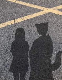 the shadow of two people standing next to each other in front of a crosswalk