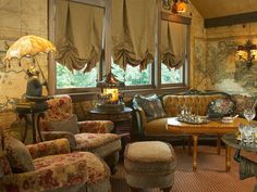 a living room filled with lots of furniture next to a window covered in drapes