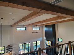 a living room filled with lots of furniture next to a tall wooden beamed ceiling