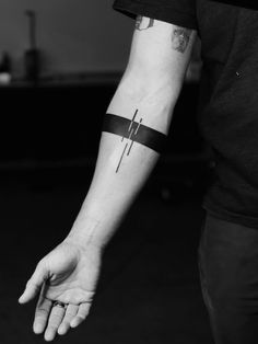 a person with a tattoo on their arm holding onto a wristband that has a cross on it