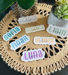 the name stickers are sitting on top of a woven mat next to a potted plant