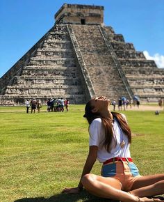 a woman sitting on the ground in front of an ancient building