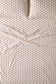 a bed with white and brown polka dot sheets