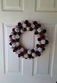 a wreath is hanging on the door with silver and red pom - poms