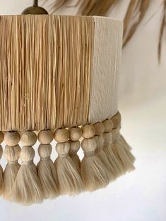 a lamp shade made out of straw and tassels hanging from a ceiling fixture