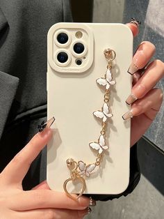 a woman's hand holding an iphone case with butterfly charms attached to the back