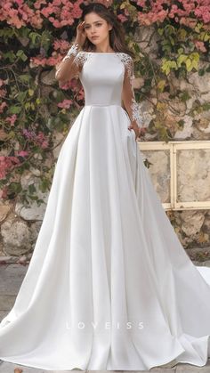 a woman wearing a white wedding dress standing in front of flowers