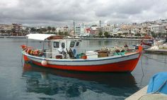 a red and white boat is docked in the water with other boats behind it on a cloudy day