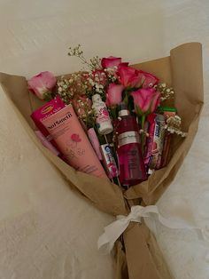 a bouquet of pink roses wrapped in brown paper with various skin care products on it