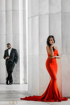 a woman in a red dress standing next to a man