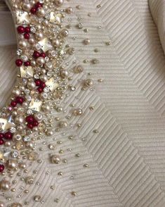 a close up view of pearls and other beads on a white fabric material with an arrow in the middle