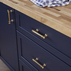 a wooden counter top sitting next to a blue cabinet with brass handles and knobs