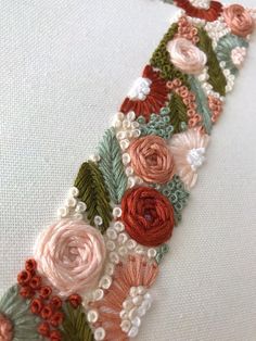 a close up of a piece of fabric with flowers and leaves on it, along with beads