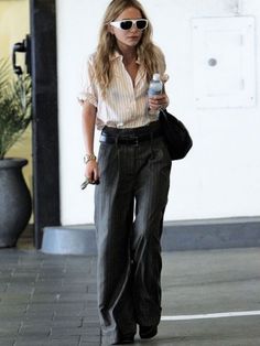 a woman walking down the street while holding a water bottle