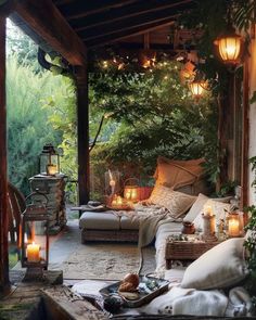 an outdoor living area with candles and pillows on the floor, surrounded by greenery