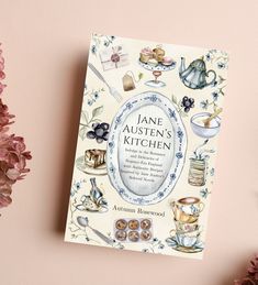 the book jane austen's kitchen is next to some flowers and other items