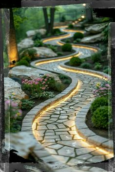 a stone path that is lit up by lights in the middle of some bushes and flowers