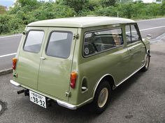 an old green car is parked on the side of the road