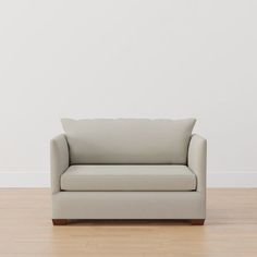 a white couch sitting on top of a hard wood floor next to a white wall