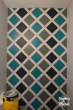 a wall painted with blue and grey squares in a bathroom next to a can of paint