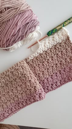 two crocheted yarns and a knitting needle on top of a white surface