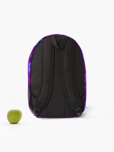 an apple sitting next to a black backpack with purple and blue designs on it, against a white background