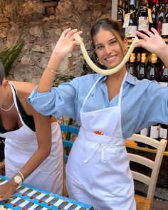 two women in aprons are preparing food at a table