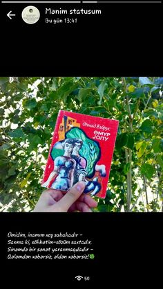 a person holding up a book in front of some trees and leaves with the title