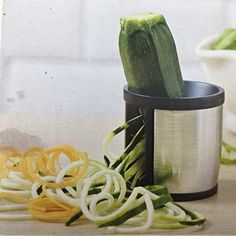 a cucumber is being cut into pieces by a canister and other vegetables