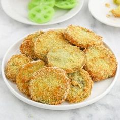 some fried food on a white plate with green peppers and broccoli in the background