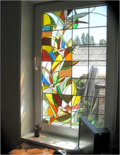 a stained glass window in the corner of a room with a desk and computer on it