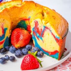 a bundt cake on a plate with blueberries and strawberries