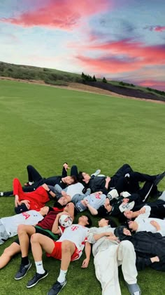 a group of young men laying on top of a lush green field next to each other