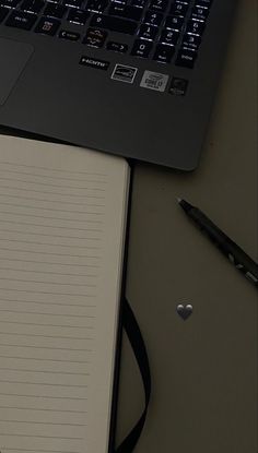 an open notebook sitting on top of a desk next to a laptop computer and pen