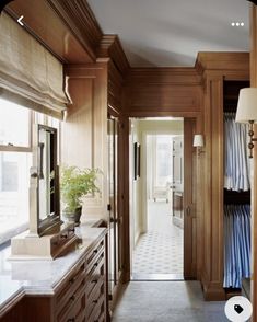 a hallway with wooden cabinets and white tile flooring next to a large mirror on the wall