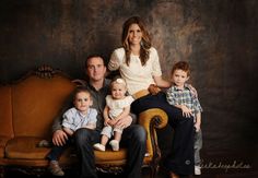 the family is posing for a photo in their old fashioned chair with two young boys and one older man